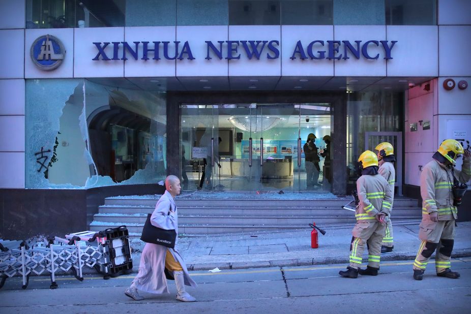 Firefighters stand outside the offices of China's Xinhua News Agency after its windows were damaged by protesters in Hong Kong on Saturday, November 2. Hong Kong riot police fired multiple rounds of tear gas and used a water cannon Saturday to break up a rally by thousands of masked protesters demanding autonomy after Beijing indicated it could tighten its grip on the Chinese territory.
