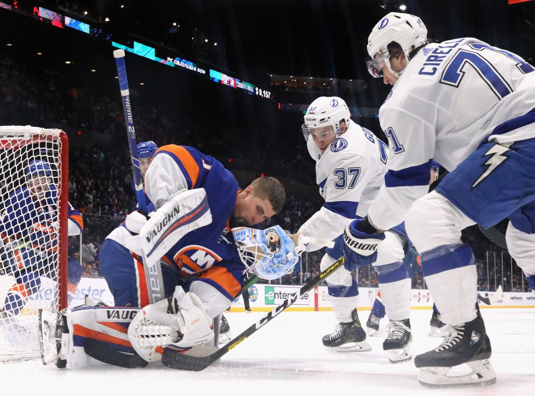 New York Islanders' Thomas Greiss' helmet falls off while stopping Yanni Gourde and Anthony Cirelli of the Tampa Bay Lightning at Nassau Veterans Memorial Coliseum on Friday, November 1, in Uniondale, New York.  <br />