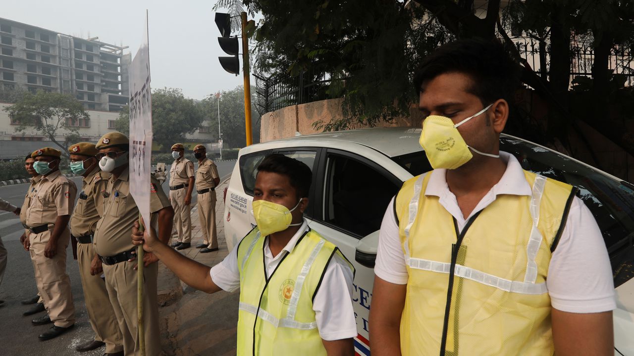 Volunteers and police wearing masks hold a banner urging drivers to obey the "odd-even" scheme.