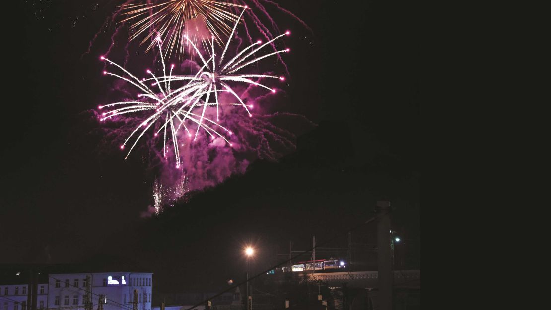 On New Year's Eve, fireworks explode overhead as a Czech Railways express train approaches Prague.