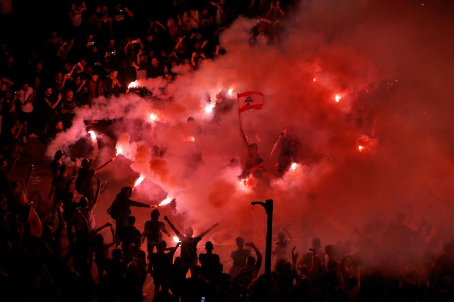 Protesters light flares and chant slogans against the Lebanese government on Sunday, November 3.