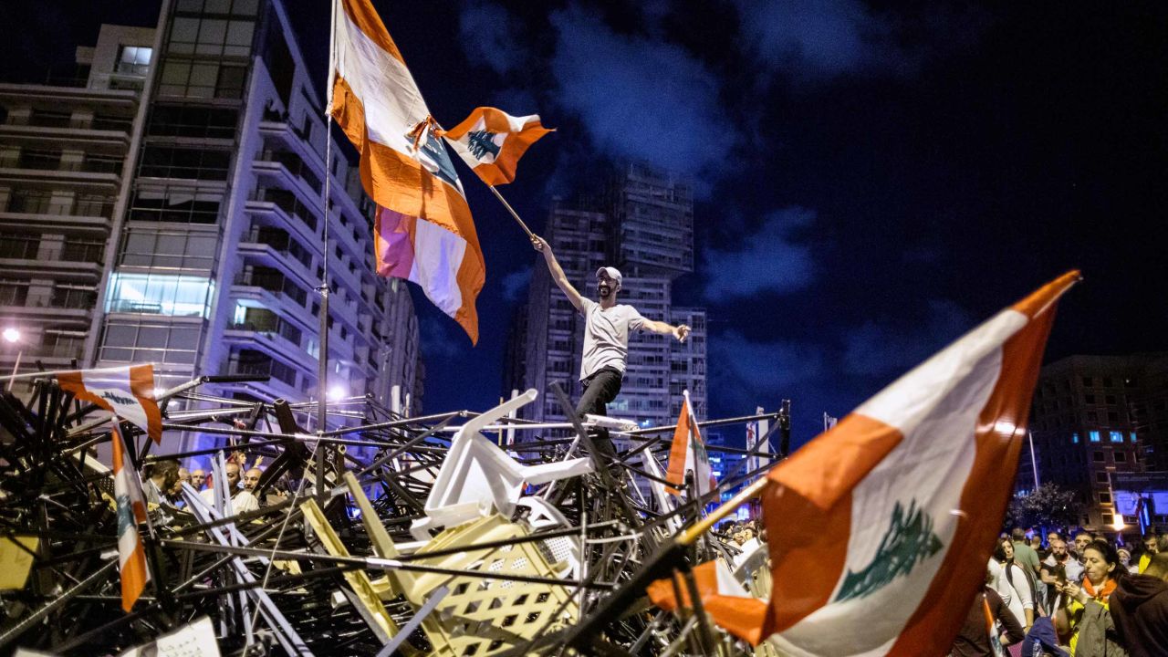 BEIRUT, LEBANON - OCTOBER 29:  An anti-government protester waves a Lebanese flag as he stands on top of a pile of broken tents in Martyrs' Square on October 29, 2019 in Beirut, Lebanon. Dozens of rioters who wanted to re-open Beirut's Ring Bridge attacked protesters earlier in the day, destroying tents and banners before being driven off by police and the Army. Protesters began to return to the square this evening. Lebanese Prime Minister earlier tendered his resignation but President Michel Aoun is yet to comment on his acceptance or otherwise.  (Photo By Sam Tarling/Getty Images)