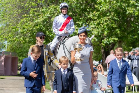Last year's winning jockey Kerrin McEvoy, who triumphed on board Cross Counter, arrives on a horse as his wife Cathy McEvoy carries the original Melbourne Cup trophy alongside their children.