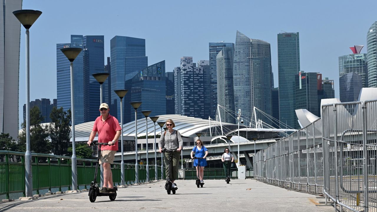 Visitors ride on an e-scooter along the Marina Bay in Singapore on February 19, 2019. (Photo by Roslan RAHMAN / AFP)        (Photo credit should read ROSLAN RAHMAN/AFP via Getty Images)