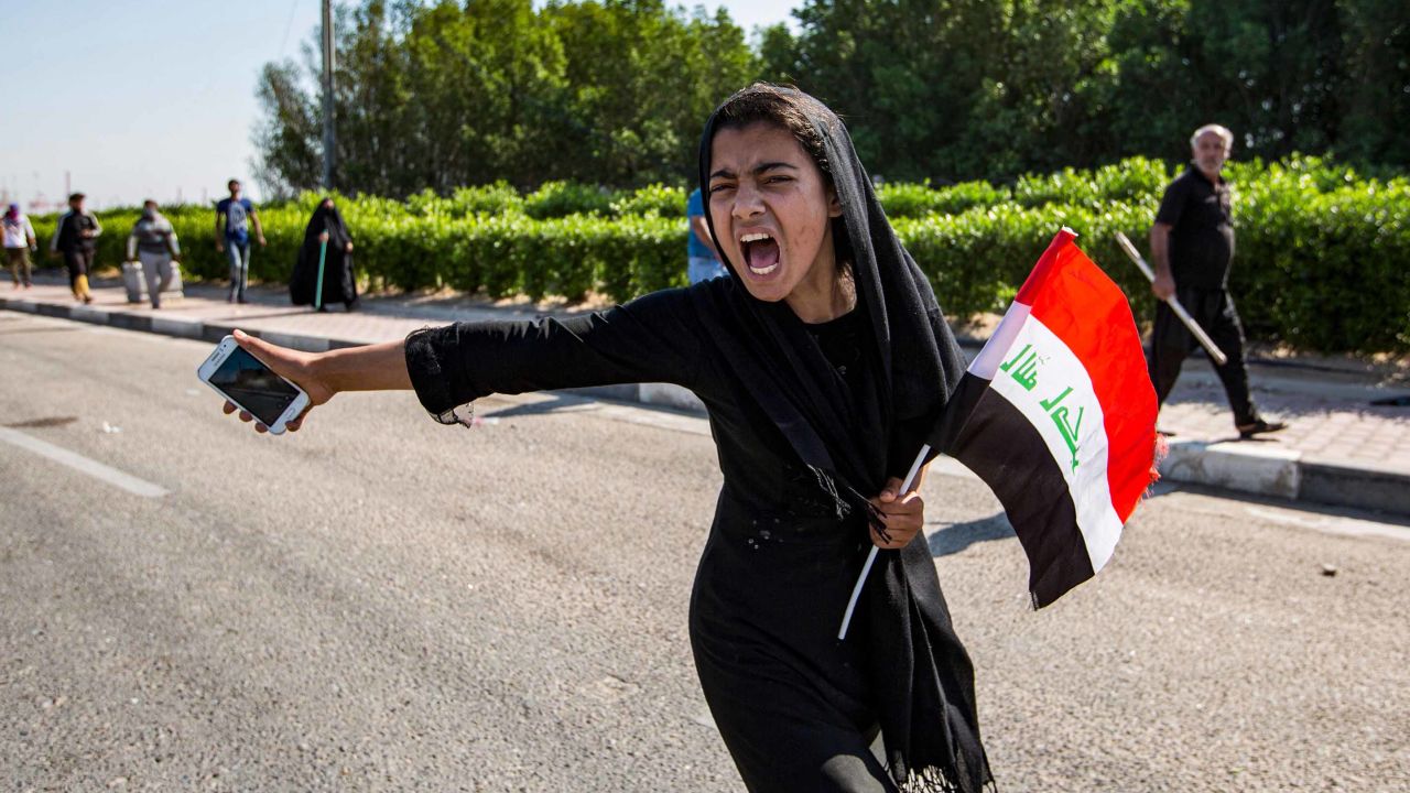 An Iraqi girl holding a national flag and a cell phone chants at a demonstration outside the port of Umm Qasr on November 5.