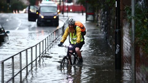 A man cycles through a flooded street Sheffield, after torrential rain in the area.
