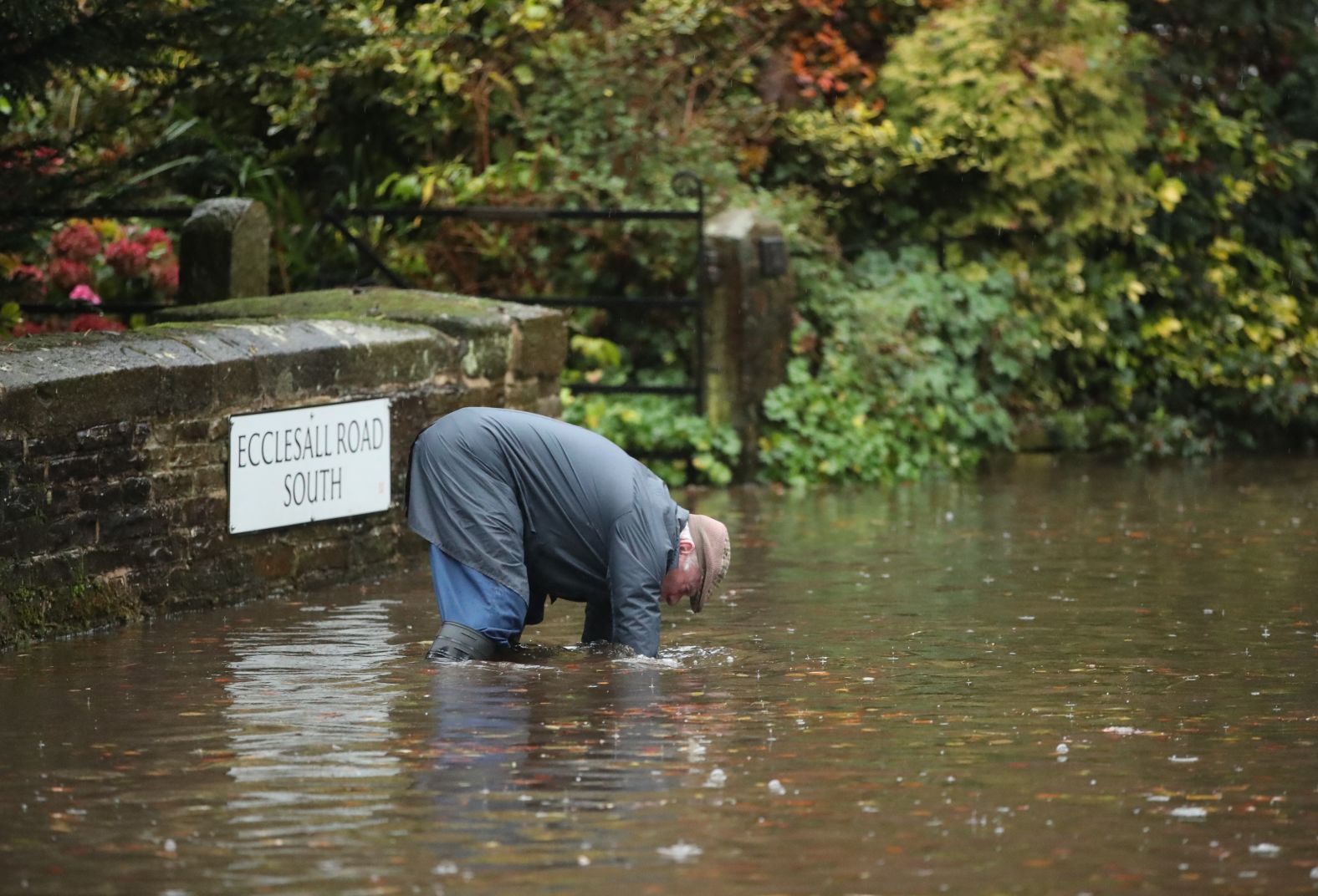 A man tries to unblock a drain on a flooded road in Whirlow, Sheffield, after torrential rain in the area on Thursday.