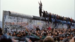 BERLIN, GERMANY - NOVEMBER 12: A man celebrates on the Berlin wall on November 12, 1989 in Berlin, Germany.(Photo by Pool CHUTE DU MUR BERLIN/Gamma-Rapho via Getty Images)