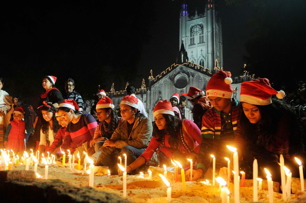 <strong>Kolkata, India:</strong> People wearing Santa hats light candles during Christmas Eve in front of St. Paul's Cathedral Church. 