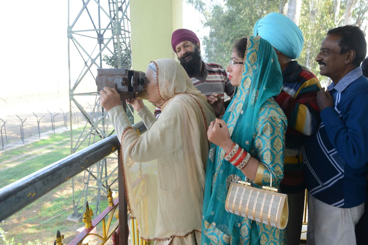 An Indian Sikh woman looks through binoculars towards the Gurdwara Kartarpur Sahib from Indian side at Dera Baba Nanak.