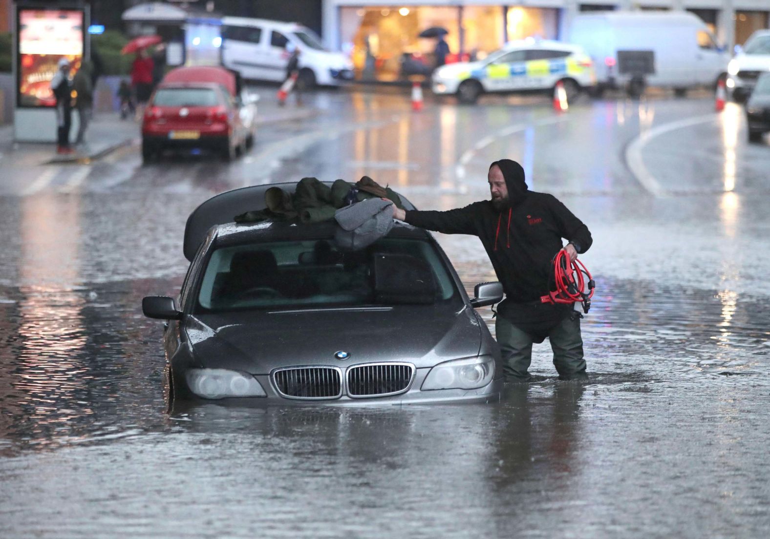A man gathers items from a partially submerged car in Sheffield.