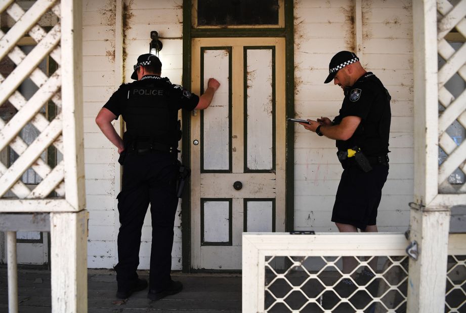 Police knock on the door of a house to warn residents of an out-of-control bushfire near Clumber on November 8. 