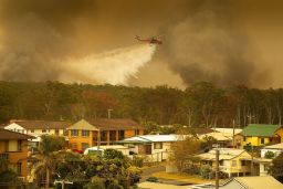 A water bombing helicopter drops water on a bushfires in Harrington, New South Wales, Australia, 08 November 2019.