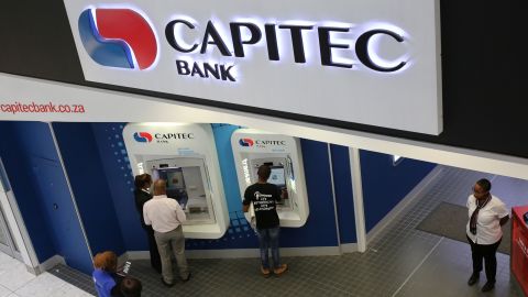 Customers draw money from an ATM outside a branch of Capitec Bank in Johannesburg.