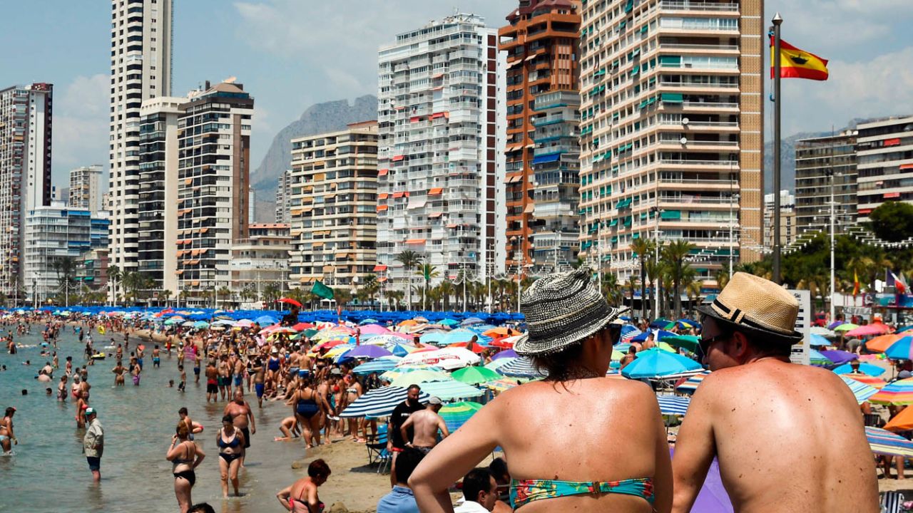 Beach-goers cool off and sunbathe on the beach of the seaside resort of Benidorm, on August 5, 2018 - Europe sweltered through an intense heatwave today, with soaring temperatures contributing to forest fires, nuclear plants closing and even threatening the Netherlands' supply of fries, although some countries experienced a slight respite. (Photo by JOSE JORDAN / AFP)        (Photo credit should read JOSE JORDAN/AFP via Getty Images)