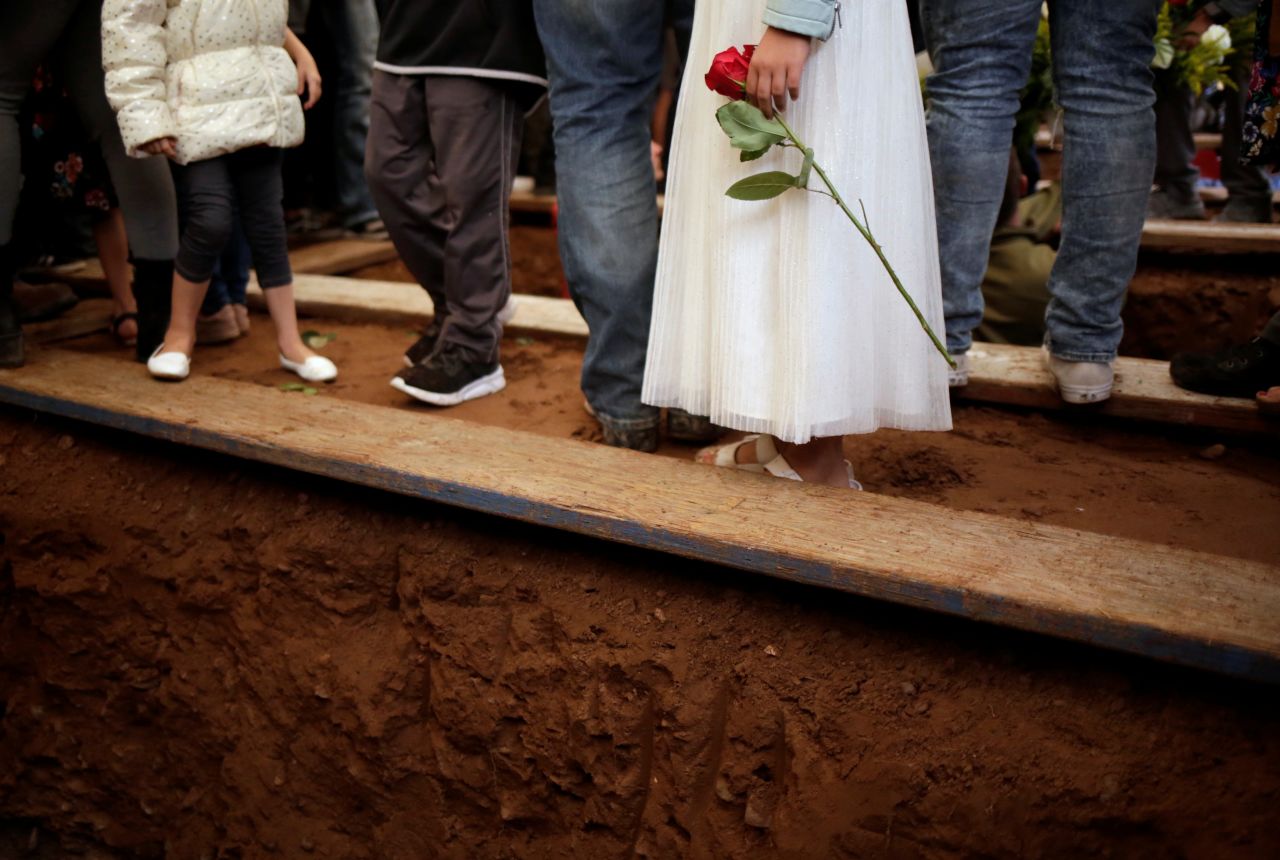 A relative holding a rose attends the service.