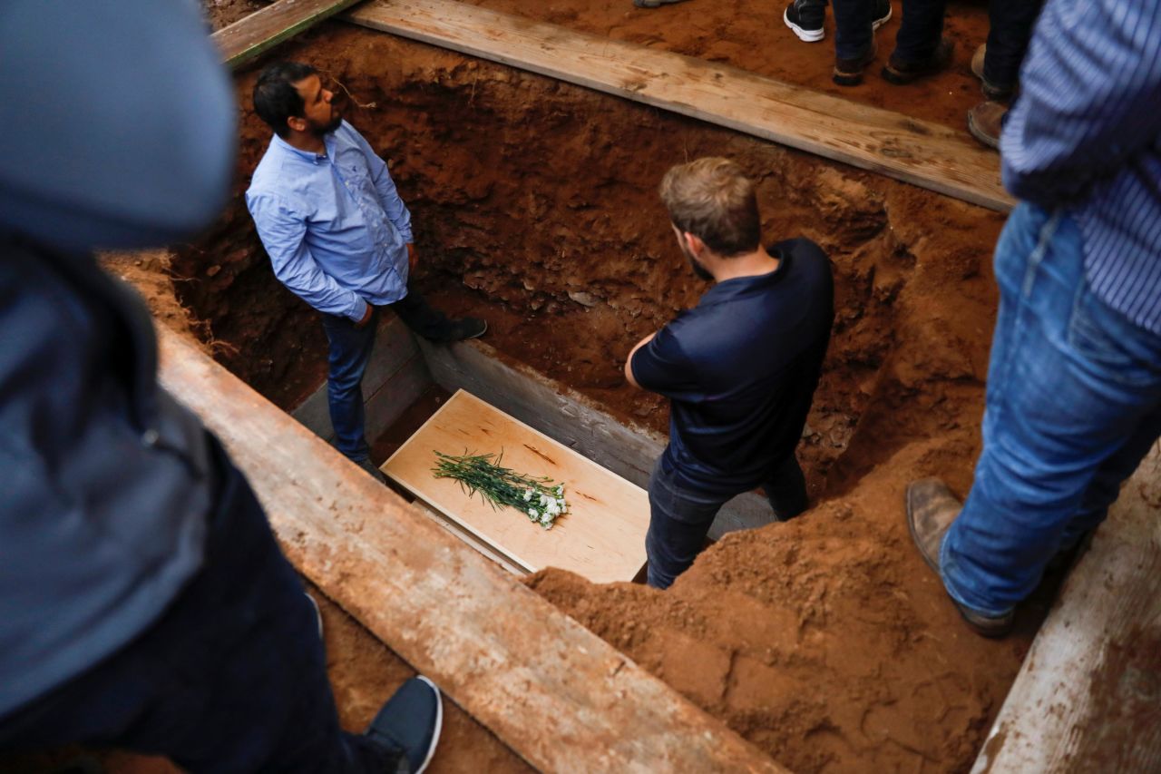 Relatives stand next to one of the coffins at the burial.