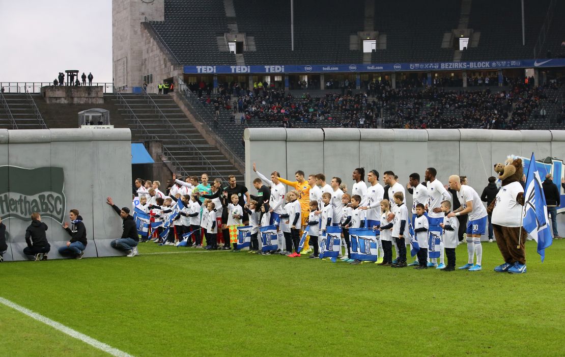 Players from Hertha Berlin and RB Leipzig line up on either side of a replica of the Berlin Wall before a Bundesliga match at the Olympic Stadium held on the 30th anniversary of the fall of the original wall.