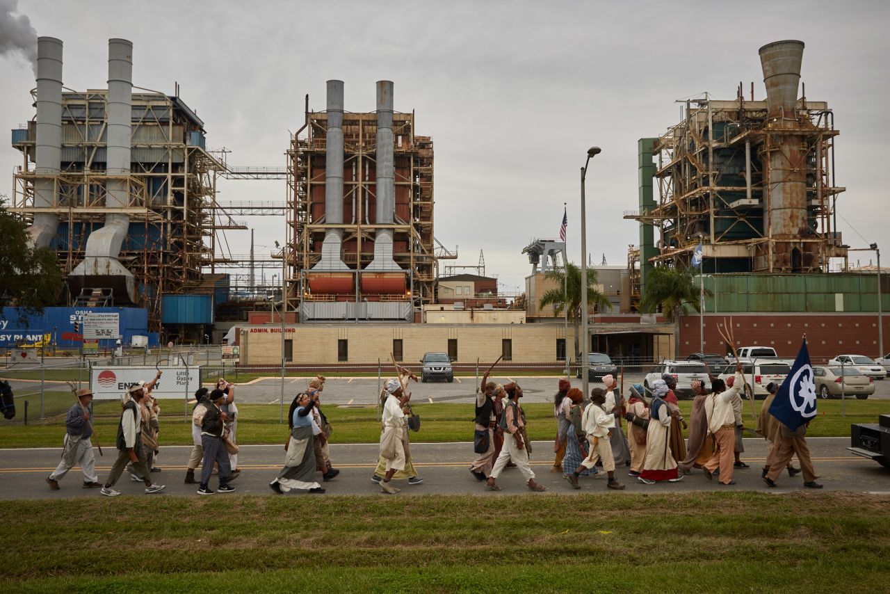 Reenactors march past Entergy's Little Gypsy power plant in Montz, Louisiana. The route they followed was once home to many plantations along the Mississippi River. These have been replaced by many industrial facilities, leading to the nickname "Cancer Alley."
