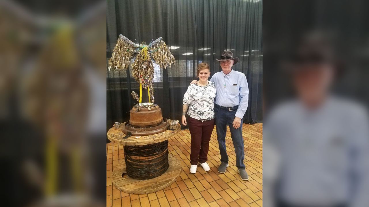 Jessie Mercer and her father, Tommie Mercer, pose next to Jessie's phoenix sculpture after the unveiling ceremony on Friday. 