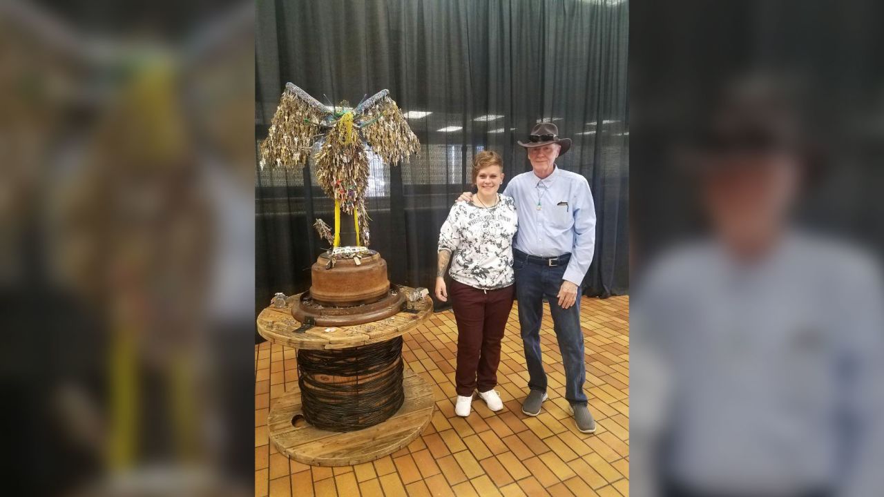 Jessie Mercer and her father, Tommie Mercer, pose next to Jessie's phoenix sculpture after the unveiling ceremony on Friday.