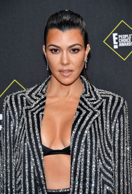 Kourtney Kardashian arrived in a glittering striped pantsuit.