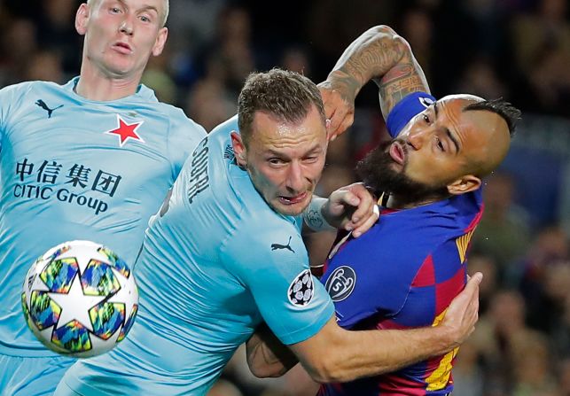 Slavia's Vladmir Coufal, center, Barcelona's Arturo Vidal, right, compete for the ball during a Champions League group F soccer match at Camp Nou stadium in Barcelona, Spain, November 5.