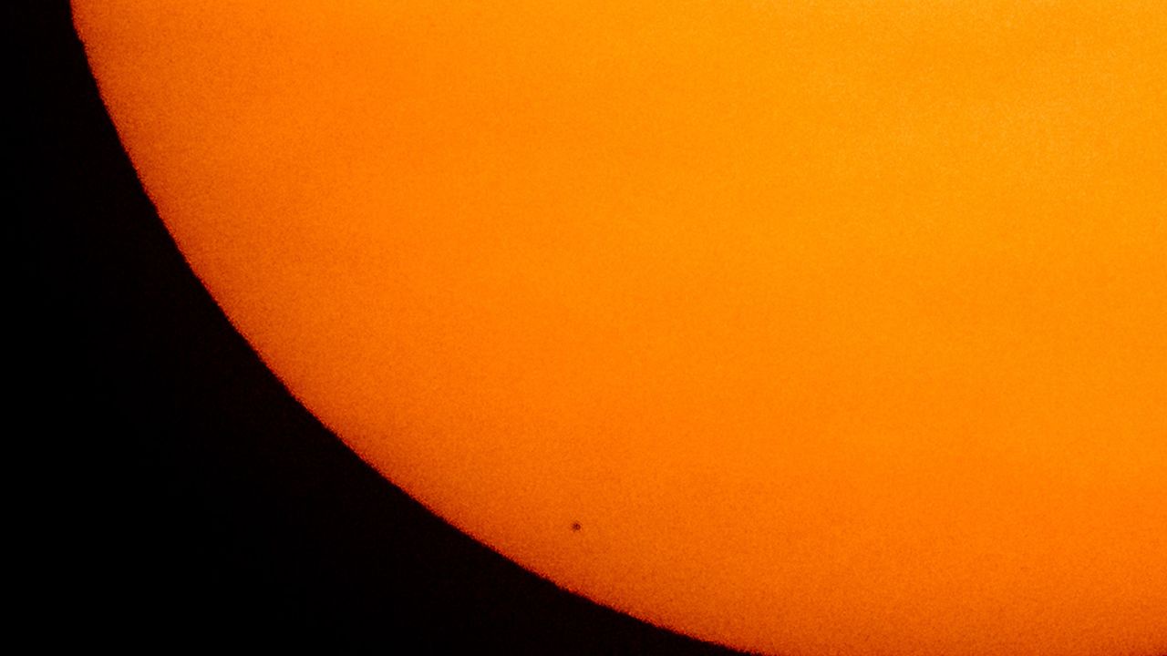 Mercury is seen in silhouette, low center, as it transits across the face of the sun on Monday. The planet last passed across the sun in 2016.