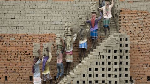 Indian labourers carry clay bricks to a brick kiln in Farakka, in the Indian state of West Bengal,  2019.