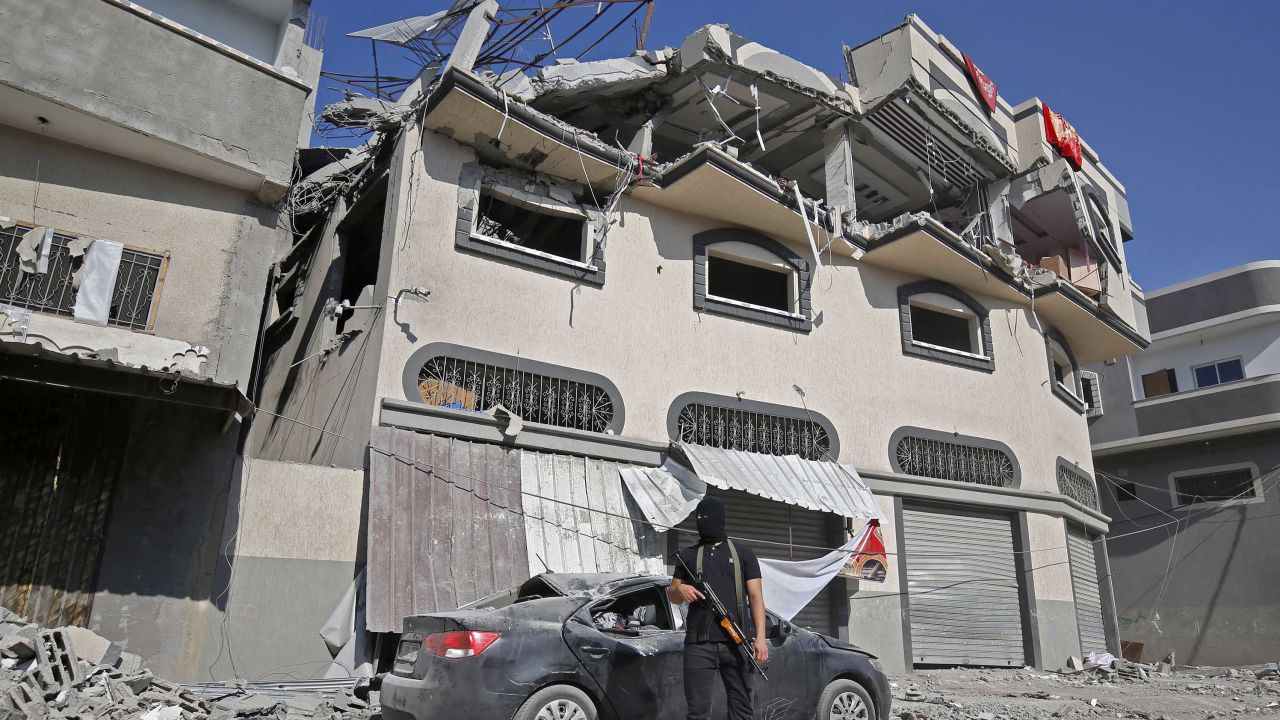 A Palestinian militant stands guard outside the house where Islamic Jihad leader Baha Abu Al-Ata was killed in a strike in Gaza.