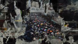 Marching anti-government protesters are seen through a window with peeled-off posters on October 1.Vincent Yu/AP