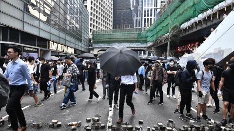 Office workers and pro-democracy protesters walk around bricks lying on a street during a demonstration in Central in Hong Kong on November 12, 2019.