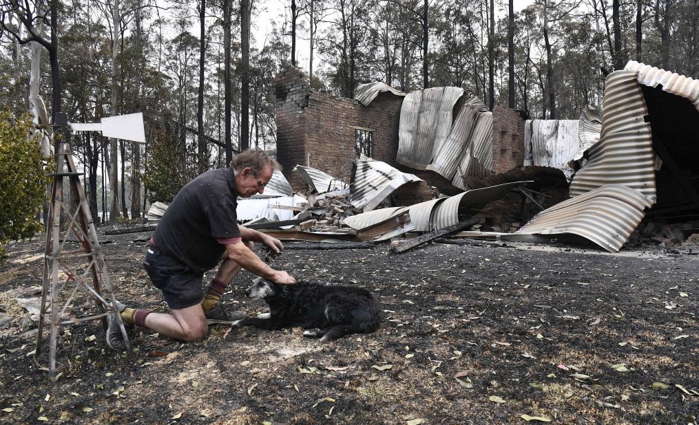 Warren Smith pats his dog after returning to find his house destroyed near Nana Glen on November 13.