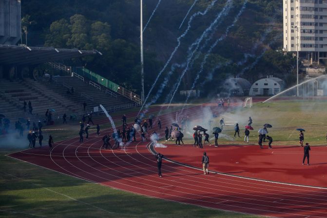 Students attempt to clear tear gas canisters fired by riot police onto a sports track during a confrontation at the Chinese University in Hong Kong on Tuesday, November 12.