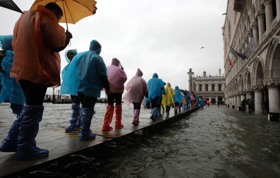 People traverse a footpath built over the flood waters.