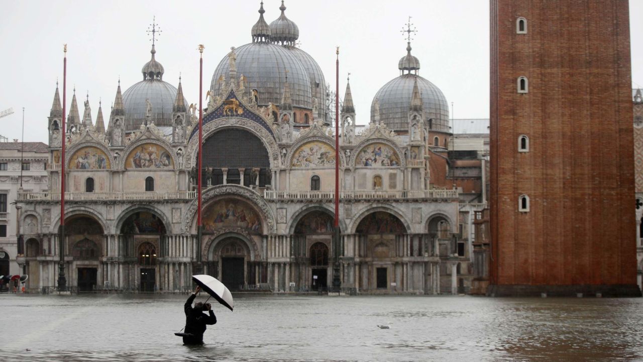 A photographer takes pictures in a flooded St. Mark's Square, in Venice, Italy, Tuesday, Nov. 12, 2019. The high tide reached a peak of 127cm (4.1ft) at 10:35am while an even higher level of 140cm(4.6ft) was predicted for later Tuesday evening. (AP Photo/Luca Bruno)