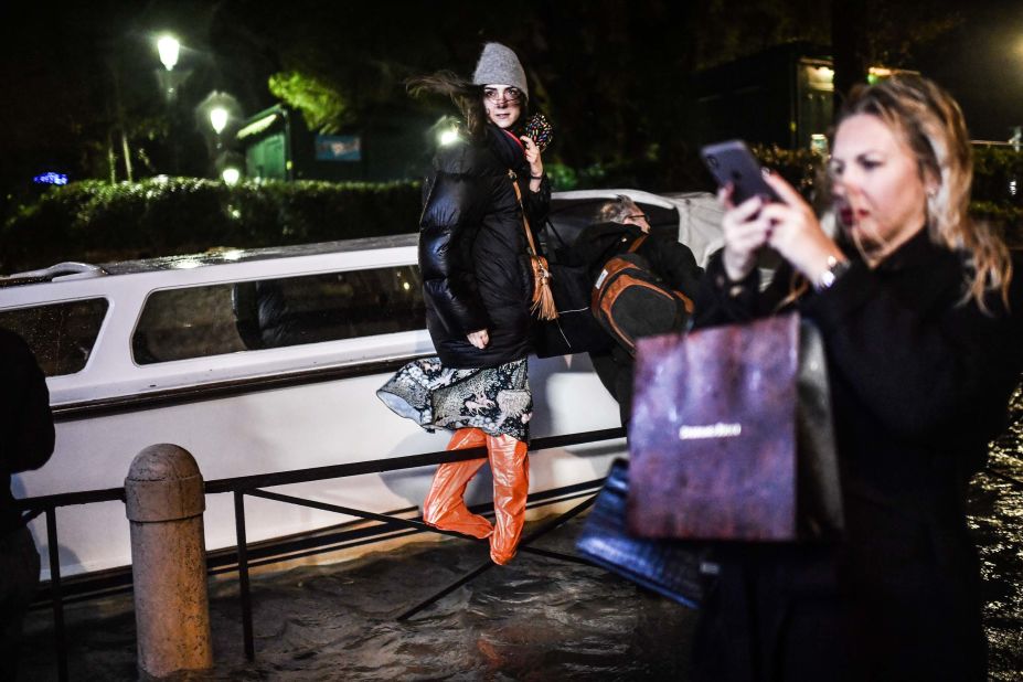 A woman stands on a barrier during an exceptional "alta acqua" high tide on November 12.