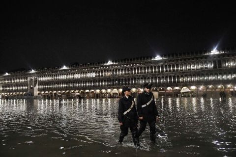 Police officers patrol a flooded St. Mark's Square during the high tide on November 12.
