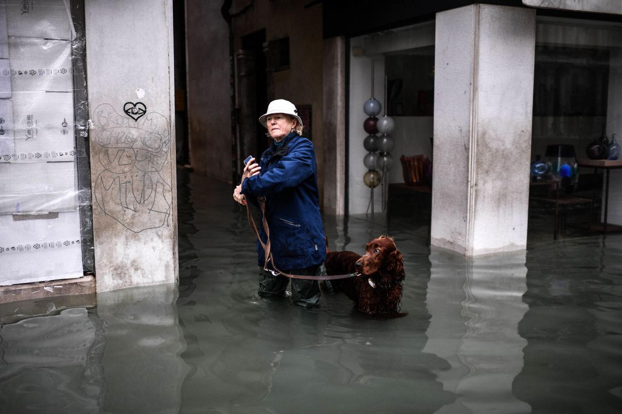 A woman walks her dog through a flooded street on November 13.