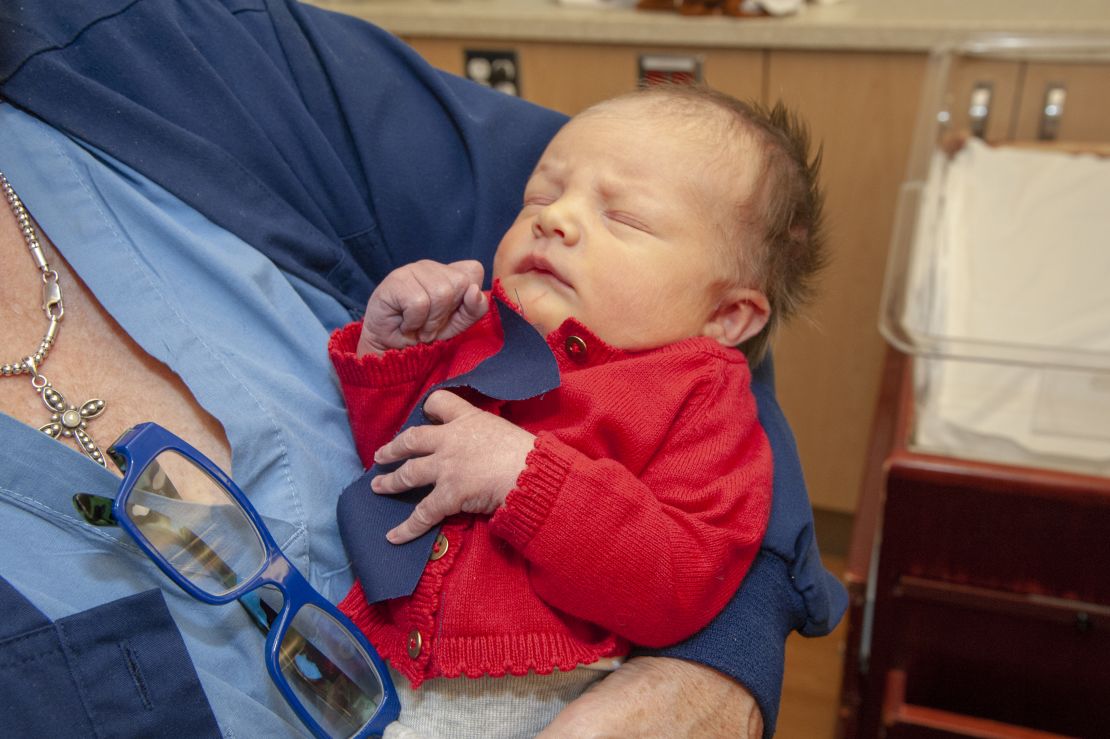 A baby at the West Penn Hospital is dressed up in a red cardigan and tie to celebrate World Kindness Day and Cardigan Day in honor of Mister Rogers.