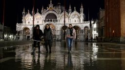 People walk across the partially flooded St. Mark's square in the lagoon city of Venice, Italy, November 14, 2019. 