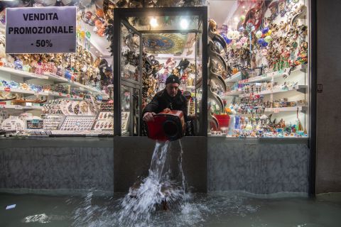 A shopkeeper throws out water from his flooded store on Wednesday, November 13.
