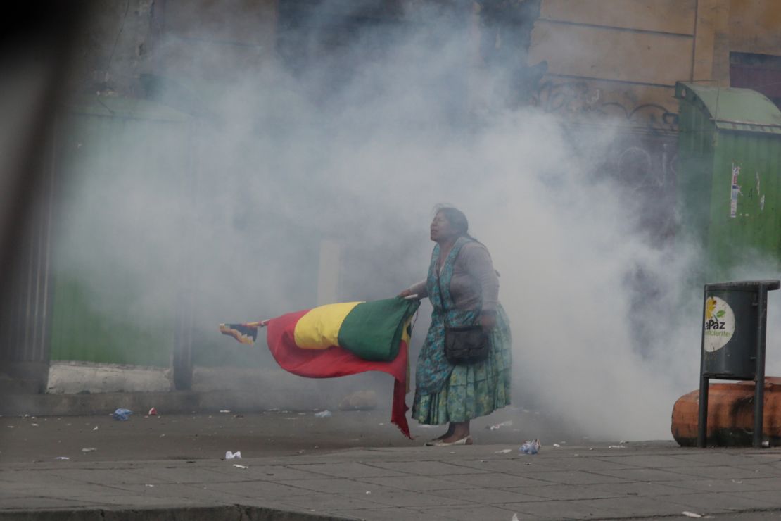 An indigenous protester is standing with a flag in tear gas smoke during Wednesday's unrest in La Paz.