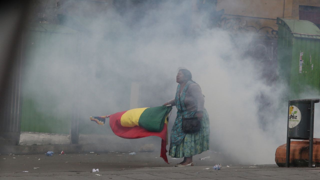 An indigenous protester is standing with a flag in tear gas smoke during Wednesday's unrest in La Paz.