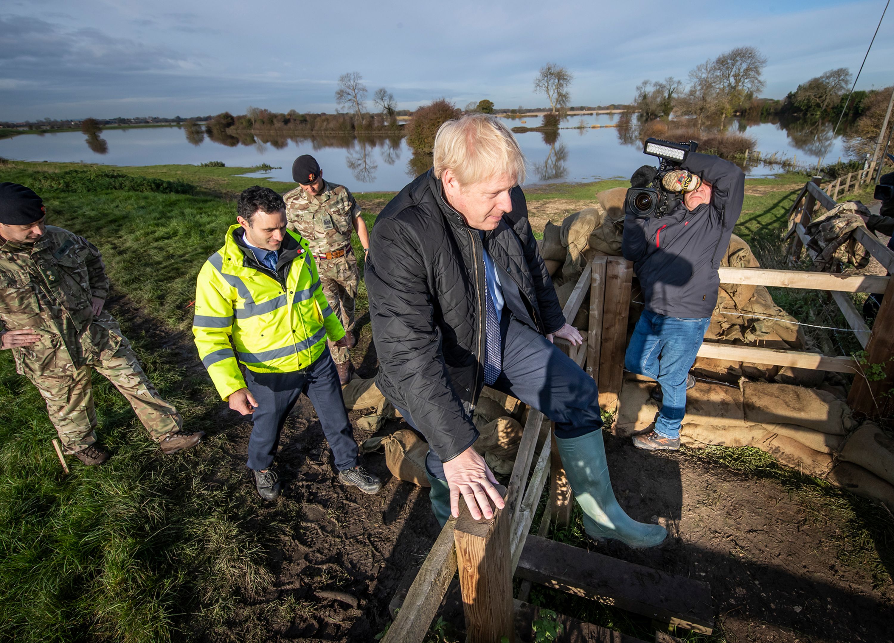Britain's Prime Minister Boris Johnson climbs over a fence during a visit to see the effects of recent flooding in Stainforth, England, on Wednesday, November 13. 
