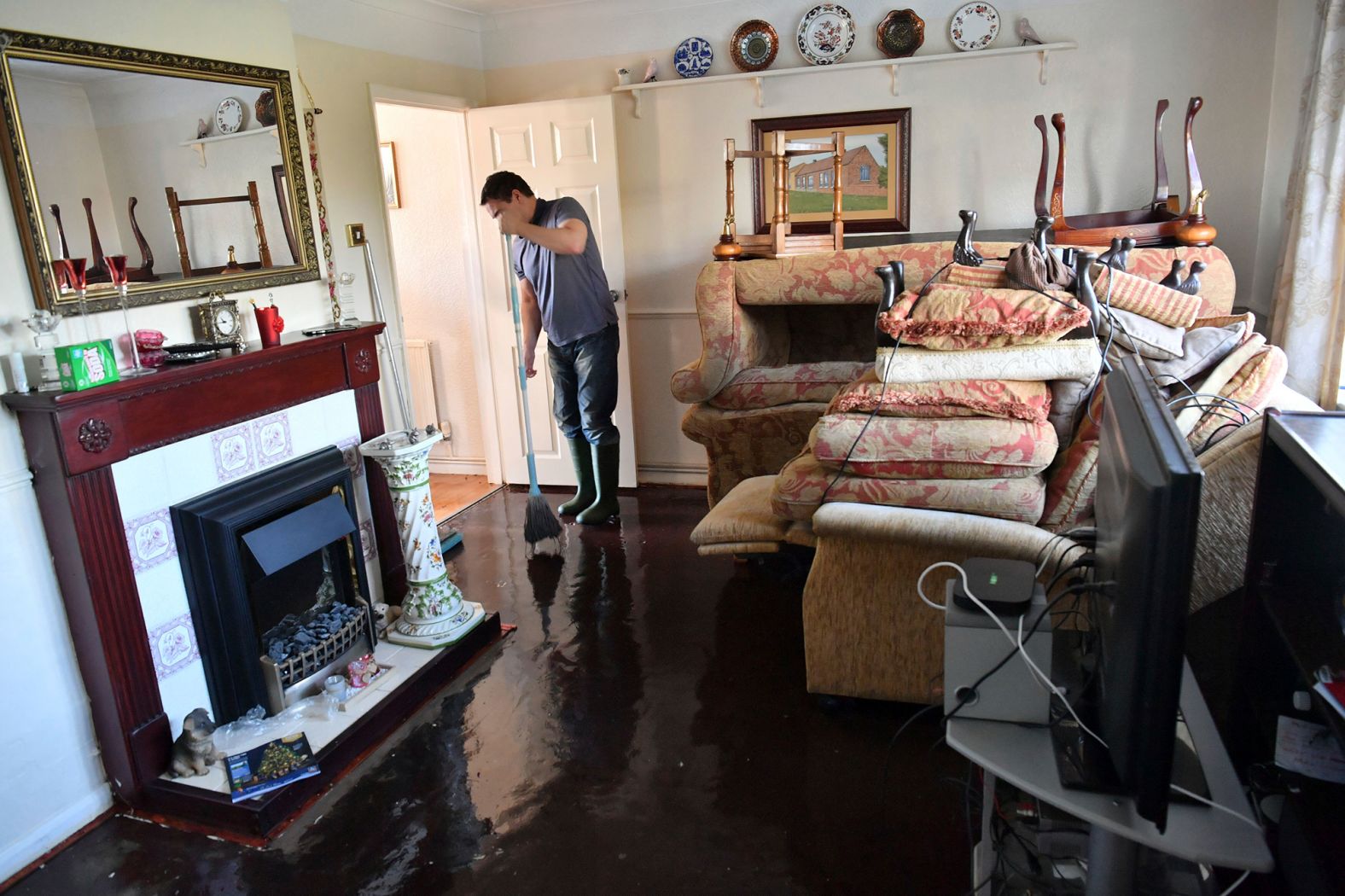 Paul Croucher mops his parents' living room after it was flooded in Fishlake, Doncaster, as parts of England endured a month's worth of rain in 24 hours on Sunday, November 10. 