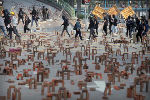 Protesters walk past barricades of bricks on a road near the Hong Kong Polytechnic University on November 14.