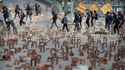 Protesters walk past barricades of bricks on a road near the Hong Kong Polytechnic University in Hong Kong, Thursday, Nov. 14, 2019. Hong Kong residents endured a fourth day of traffic snarls and mass transit disruptions Thursday as protesters closed some main roads and rail networks while police skirmished with militant students at major universities. (AP Photo/Kin Cheung)