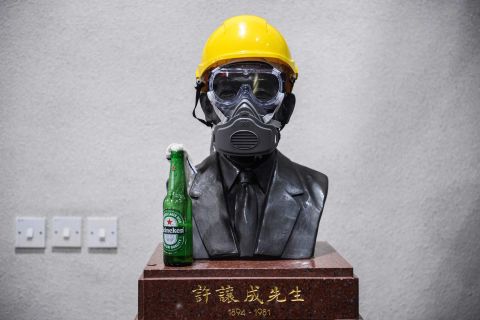 A Molotov cocktail, a gas mask and a yellow construction helmet are placed upon a bust of late hotel tycoon Hui Yeung Shing at the campus of The Chinese University of Hong Kong on November 13.