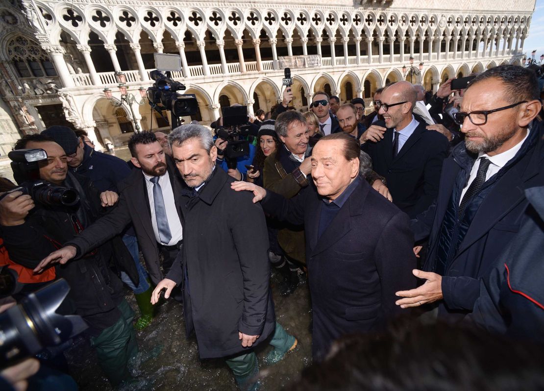 Former Italian prime minister Silvio Berlusconi is escorted by Luigi Brugnaro through the November 2019 floods